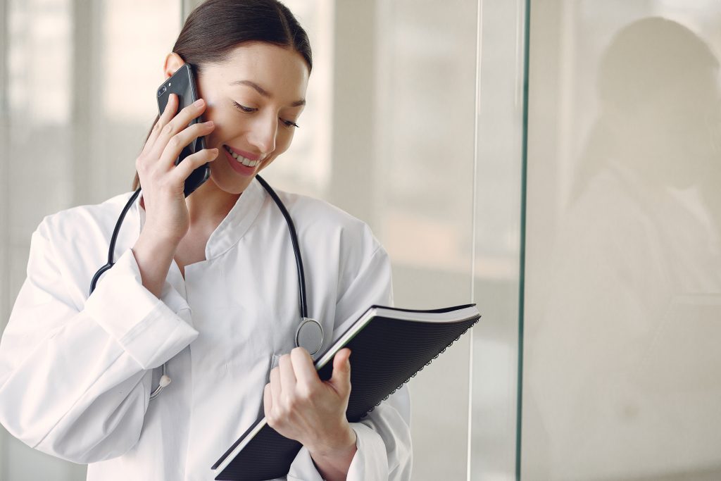 Female on-call doctor in Pererenan speaking on the phone while reviewing patient notes at Nawadipa Medical Care.